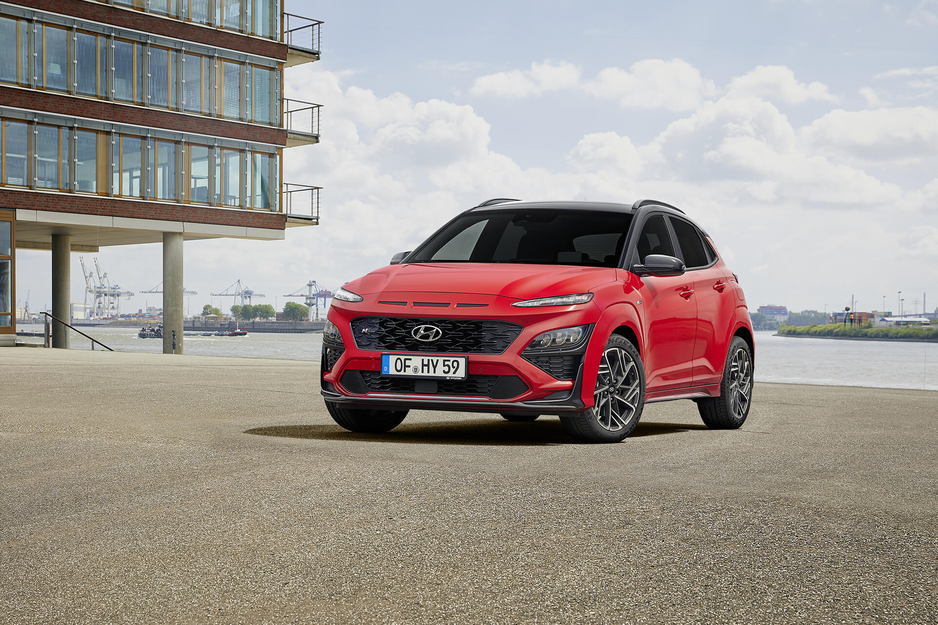 Hyundai Kona N Line zaparkovaný v průmyslovém prostředí, vedle moderní prosklené budovy.